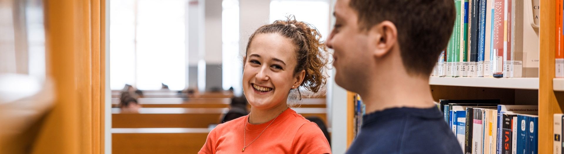 studente e studentessa tra gli scaffali della biblioteca